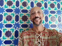 Image of Giba standing in front of an artistic tile wall